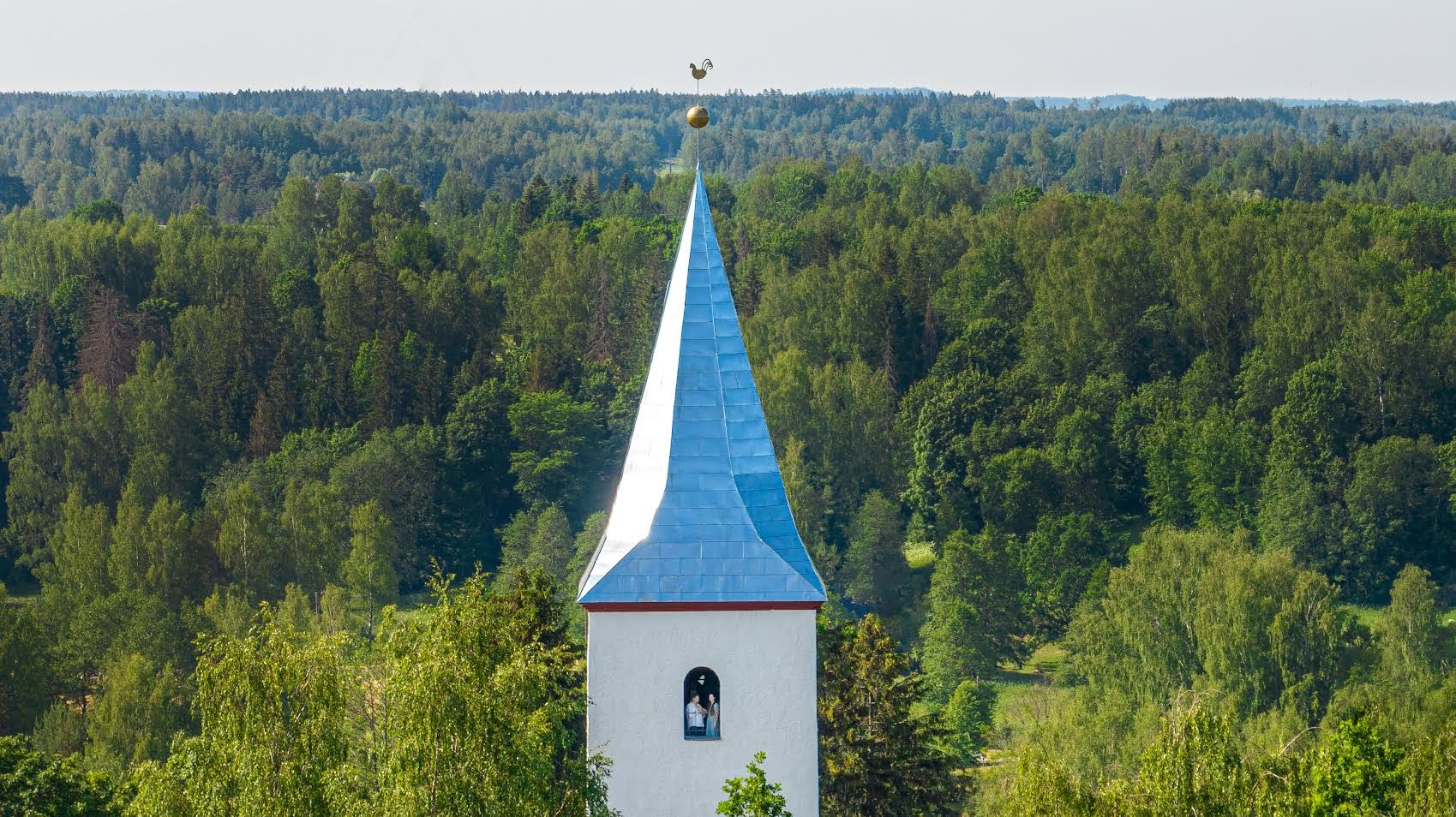 Rõuge kirikutorn sinise katusega rohelises suviseks metsas