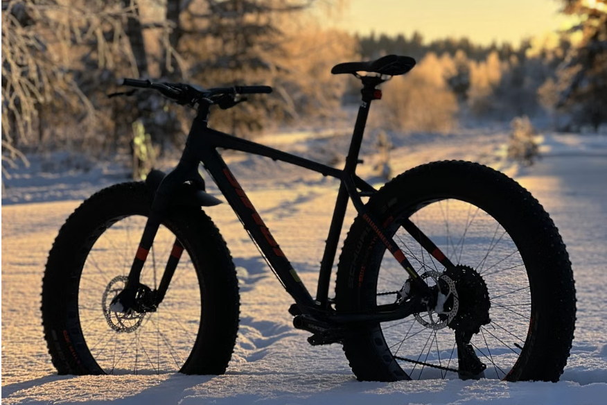 Fatbike talvisel metsateel lumeseljas päikeseloojangus