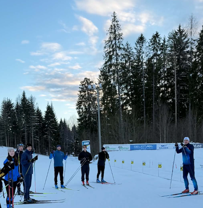 Grupp suusatajaid lumisel rajal kuusemetsa ääres